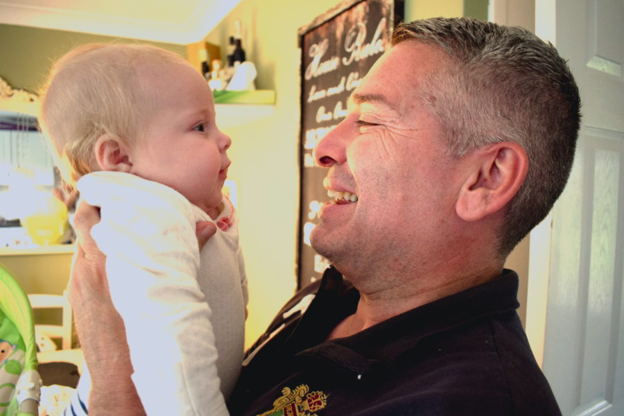 Father holding baby up to face him, smiling and talking to one another