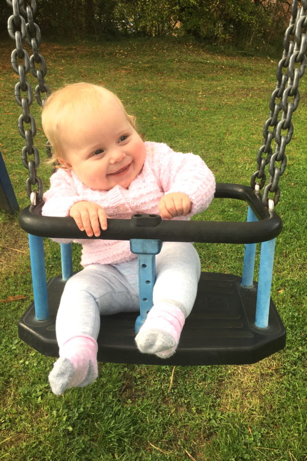 baby sitting on a swing, laughing