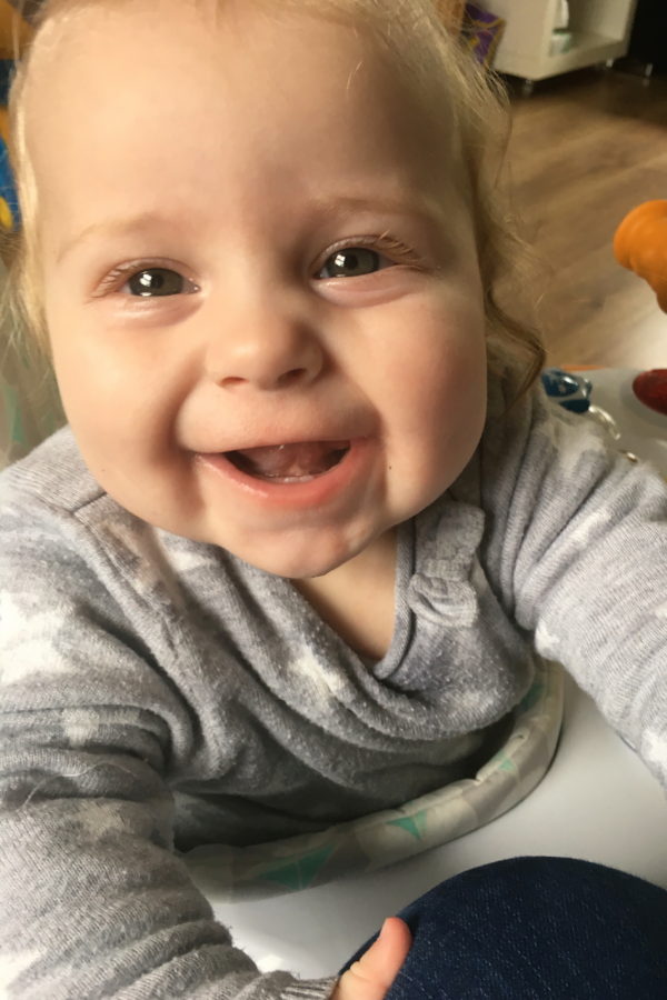 nine month old baby girl, in walker, looking up and laughing