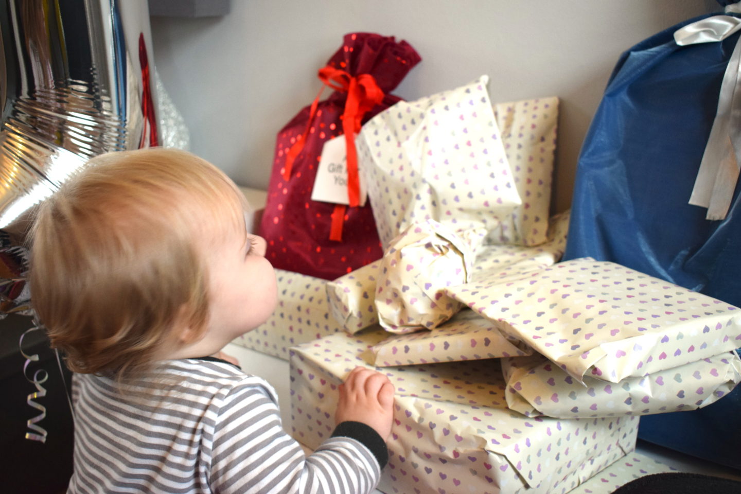 one year old girl, looking at pile of birthday presents