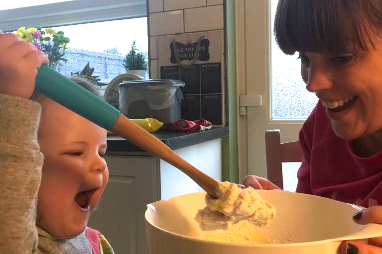 Mother and daughter making dairy and soya free easter cookies, mixing in a bowl and laughing together