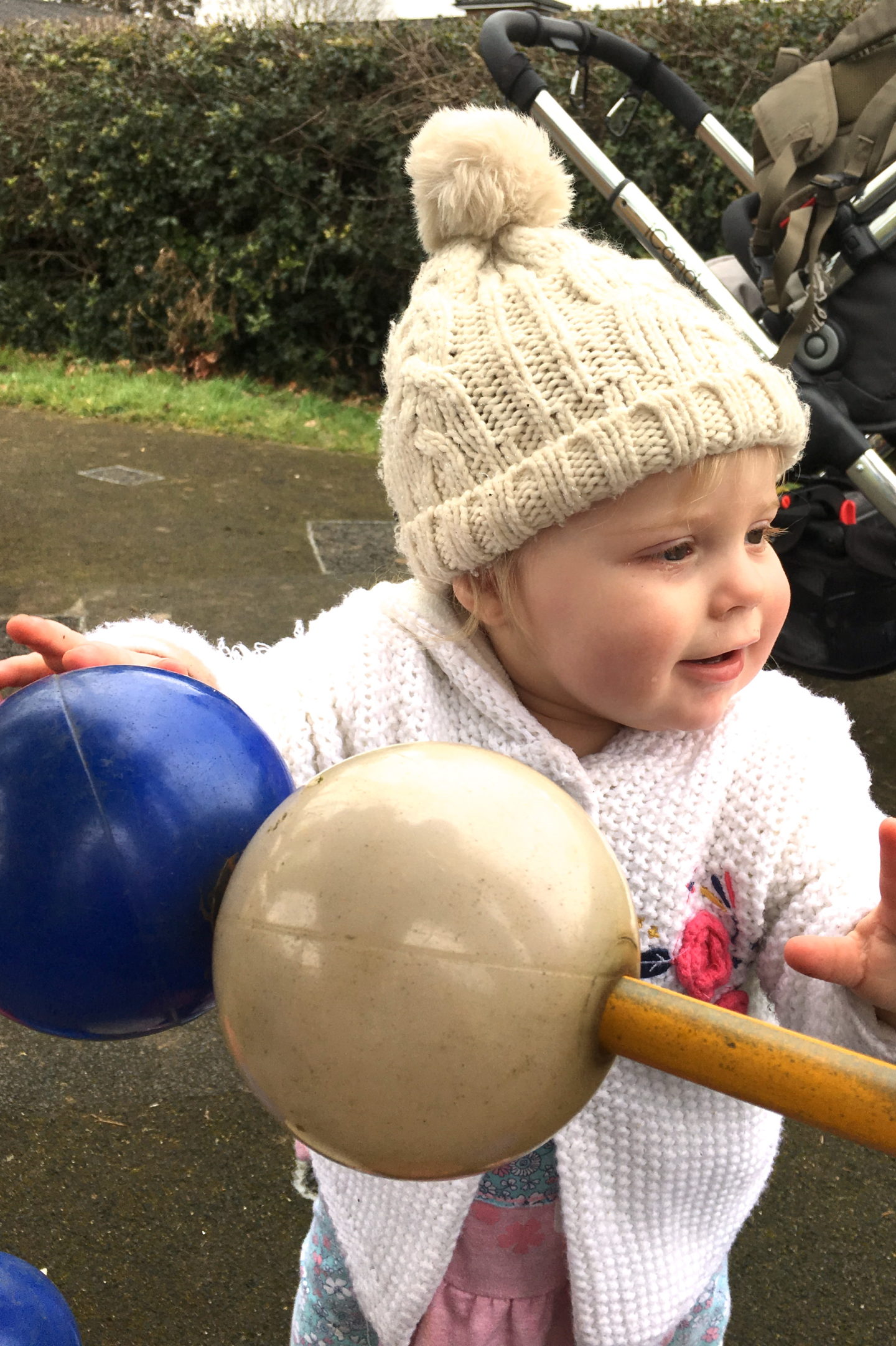 one year old girl in bobble hat, playing with oversized abacus