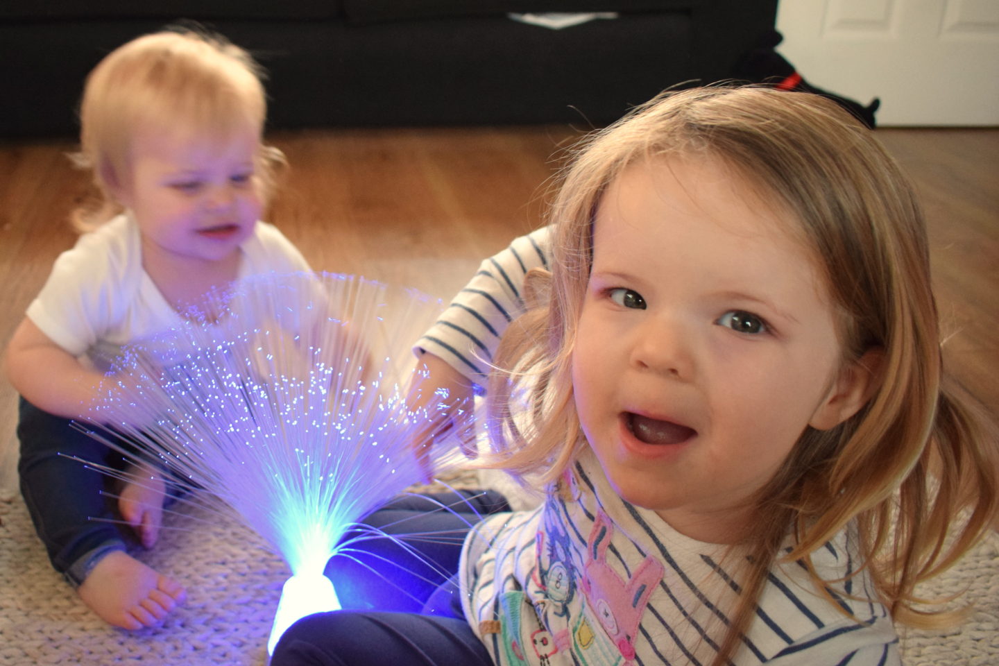 sisters playing with fibre optic lamp and laughing