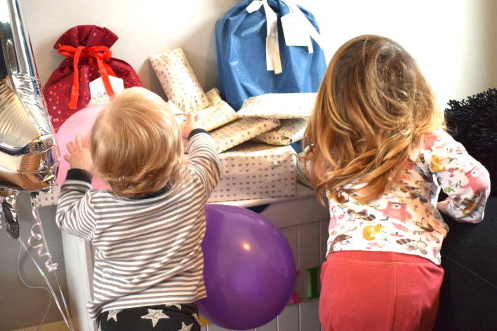 sisters standing next to each other, backs to camera, looking at a pile of birthday gifts