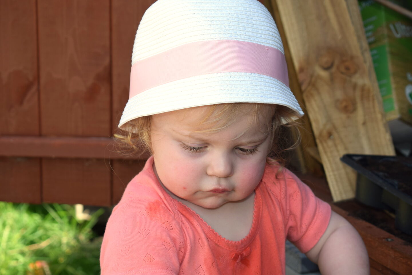 14 months old girl in sunhat, looking down