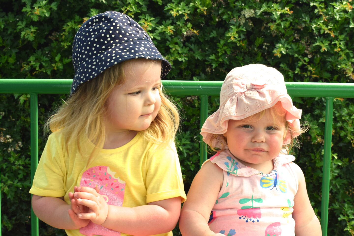 Two and one year old sisters sitting on a park bench together