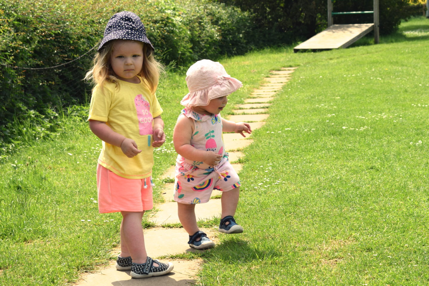 two and one year old sisters walking together in the park
