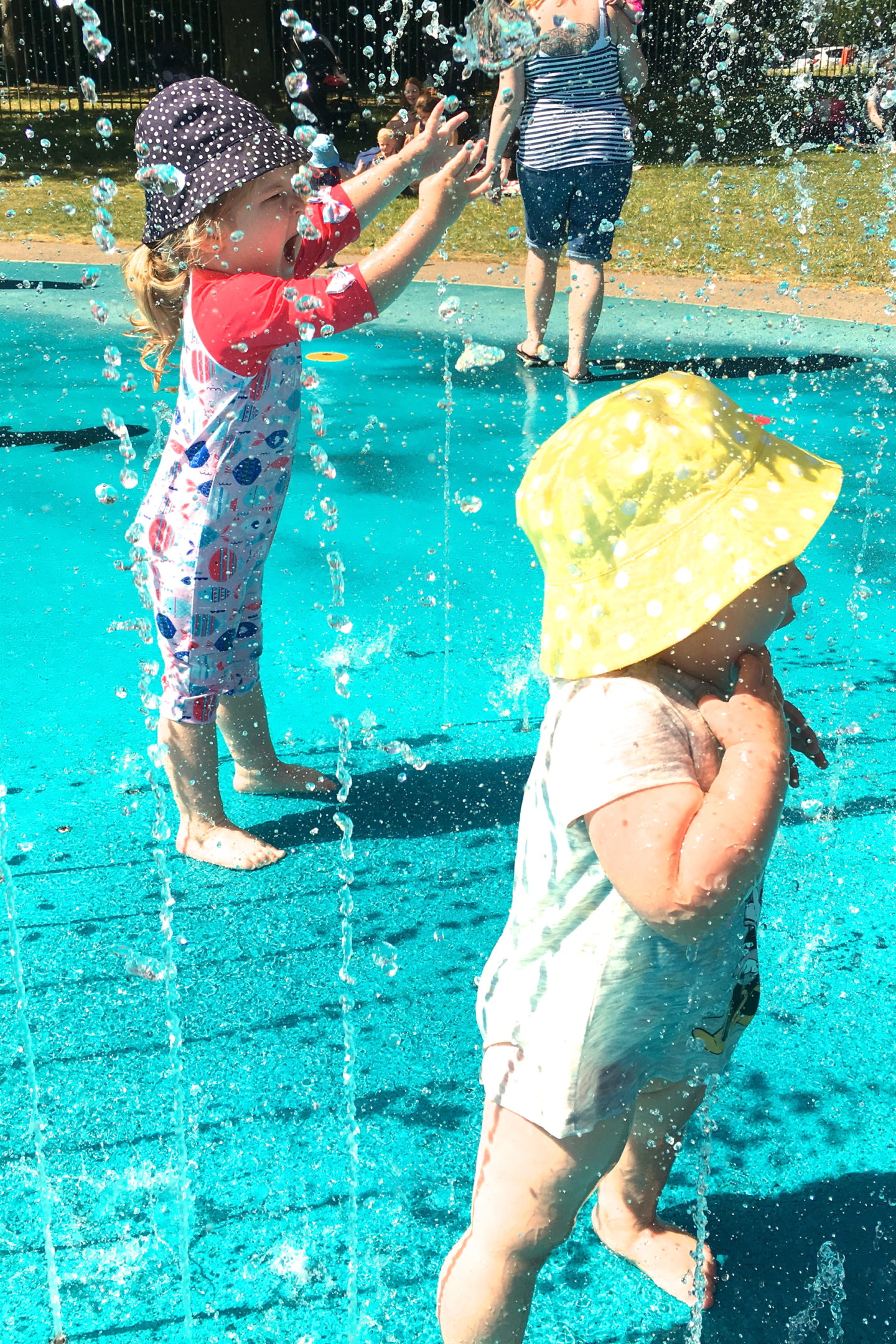 two sisters playing in the jets at a splash park
