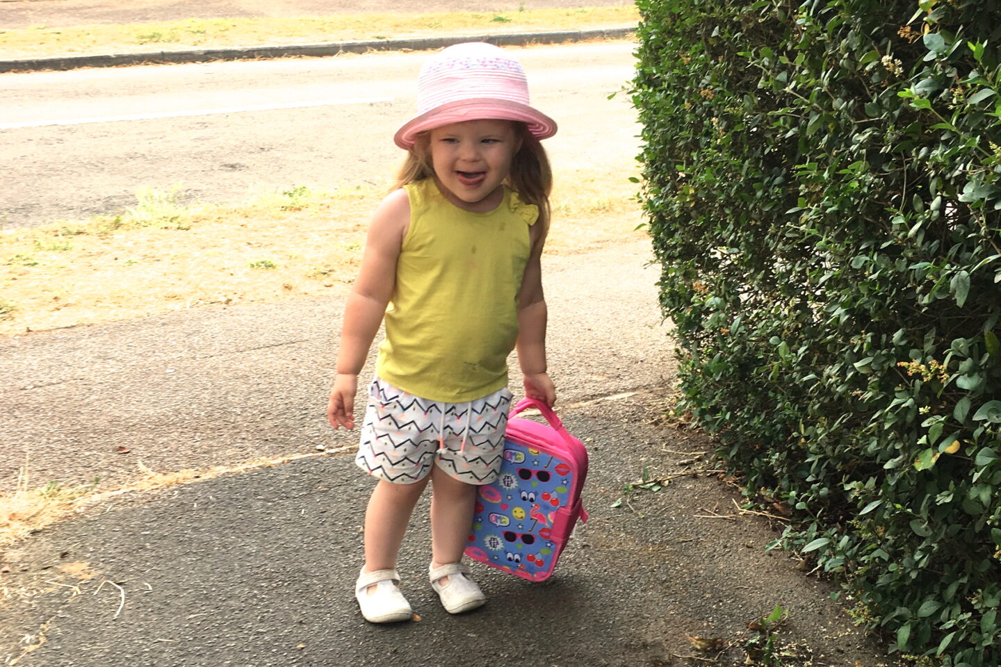 toddler girl in sunhat, holding lunch bag for weekly gratitude