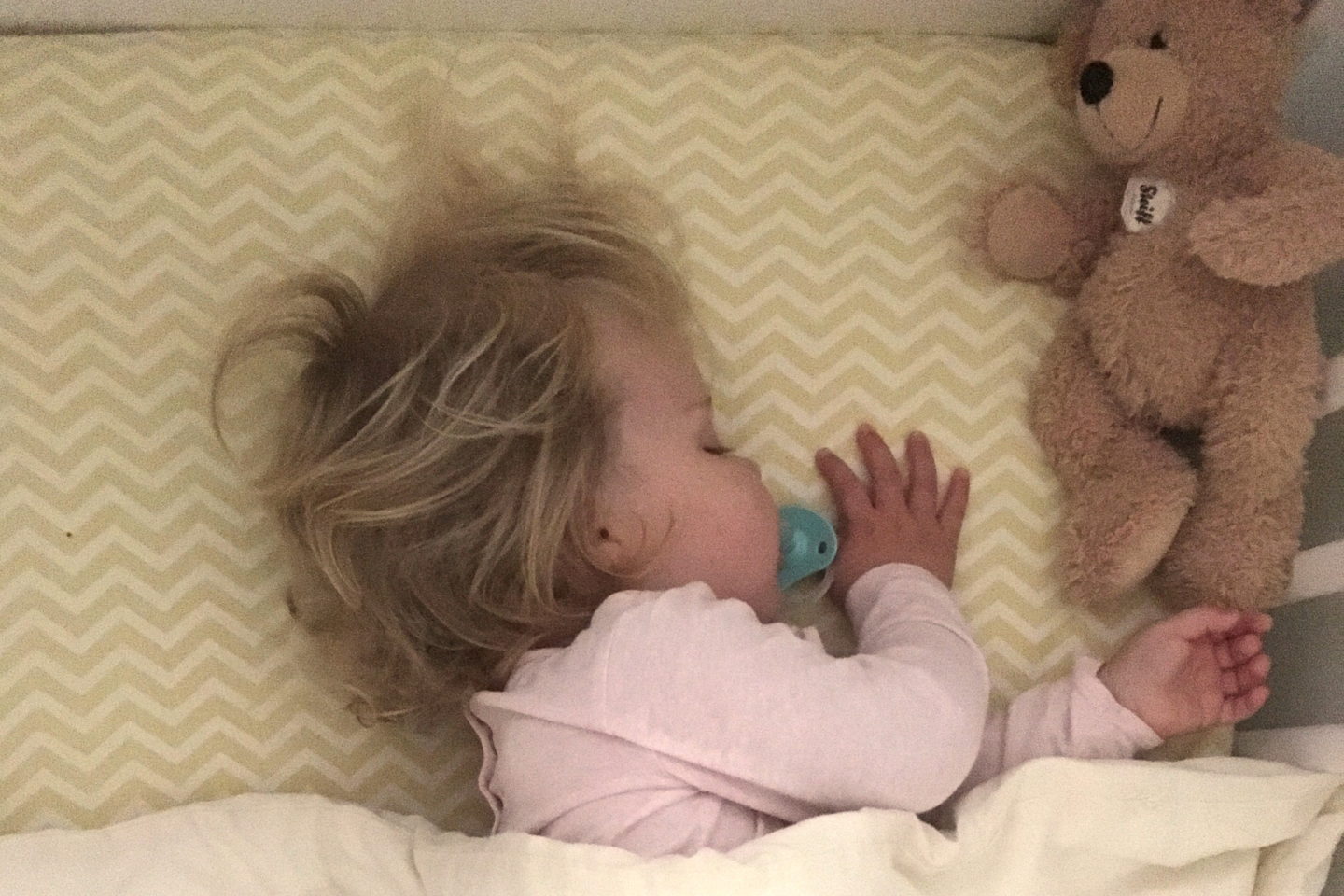 18 month old girl sleeping in cot under duvet