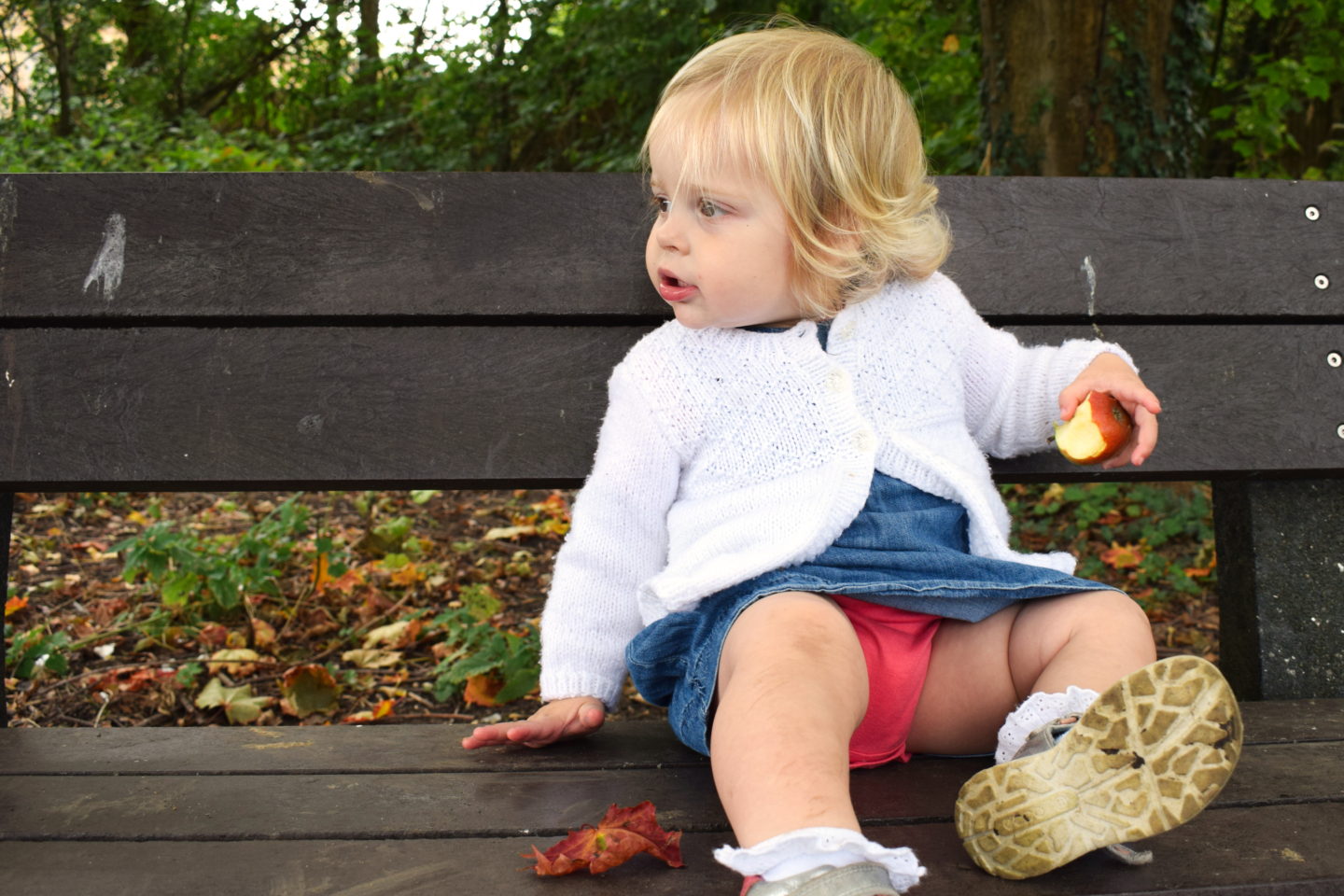 18 month old girl, sitting on bench, eating apple