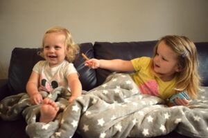 Three and one year old sisters in Snuggle Sac on the sofa
