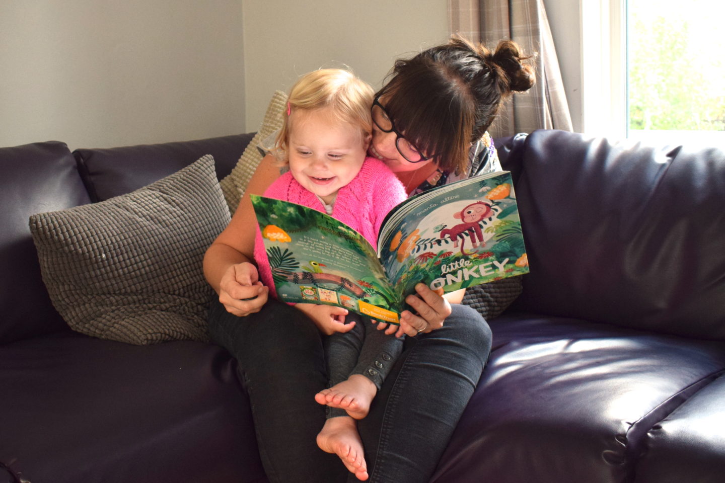 mother laughing with one year old on her lap, during time to read