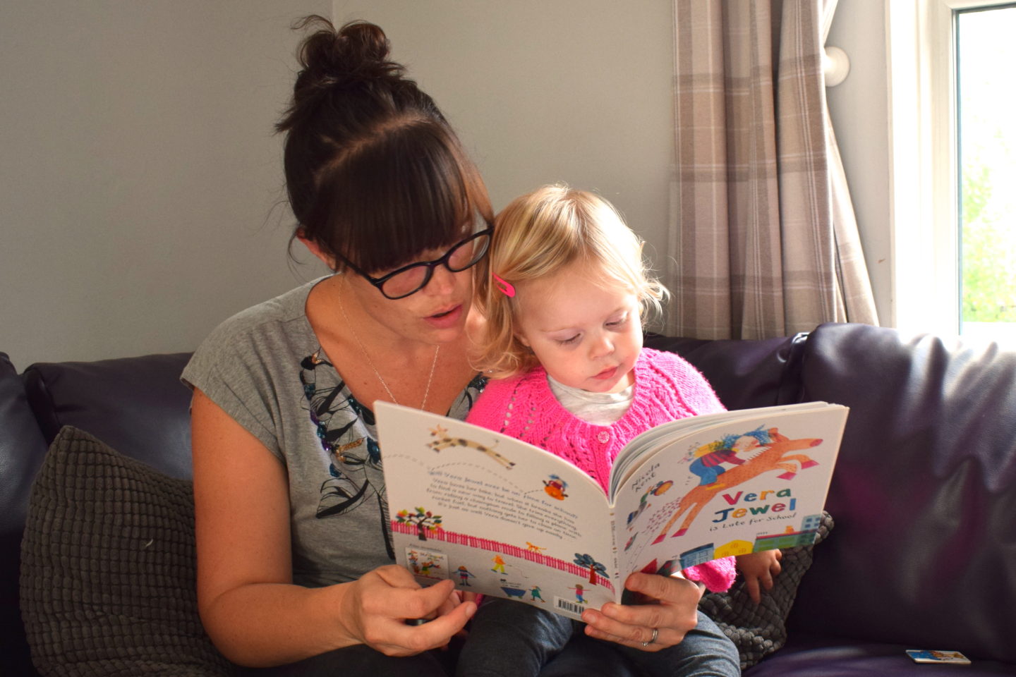 mother making time to read with one year old on her lap