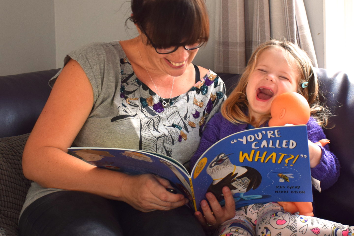 three year old laughing at a story during time to read with mother