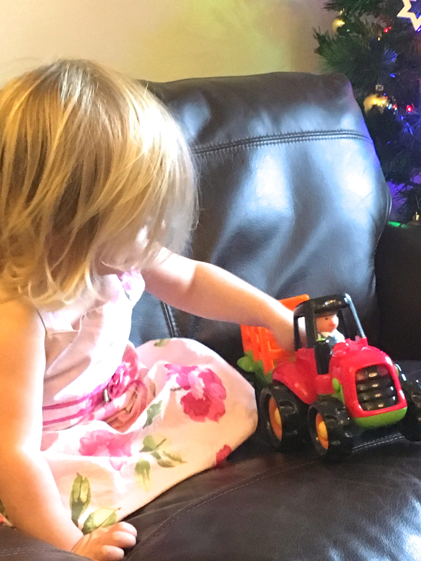 22 month old in pink dress playing with tractor toy