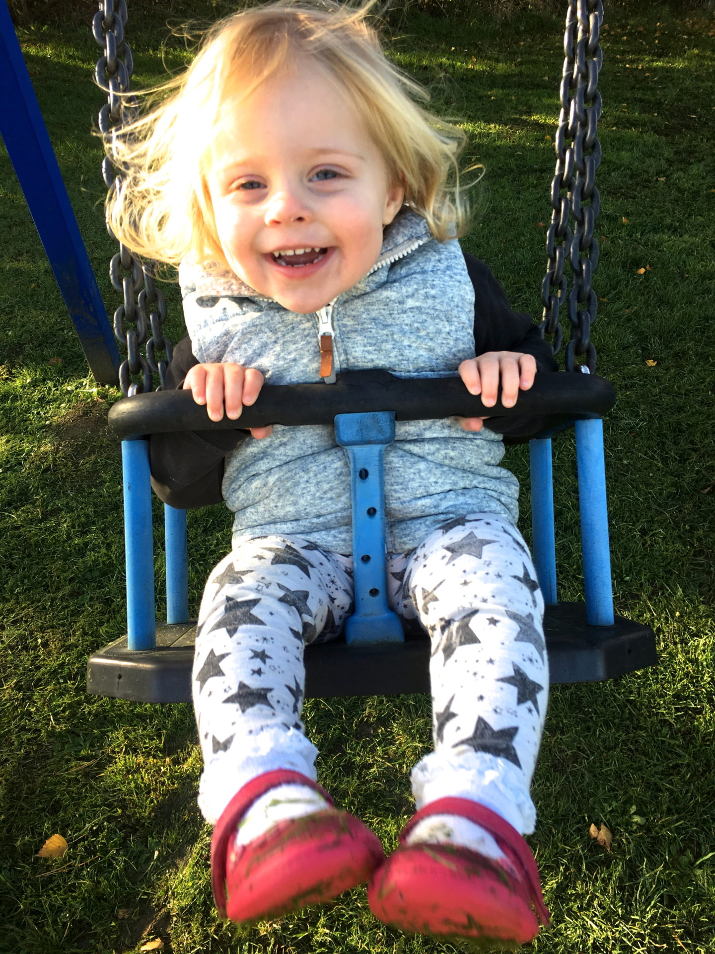 22 months old girl on a swing, smiling