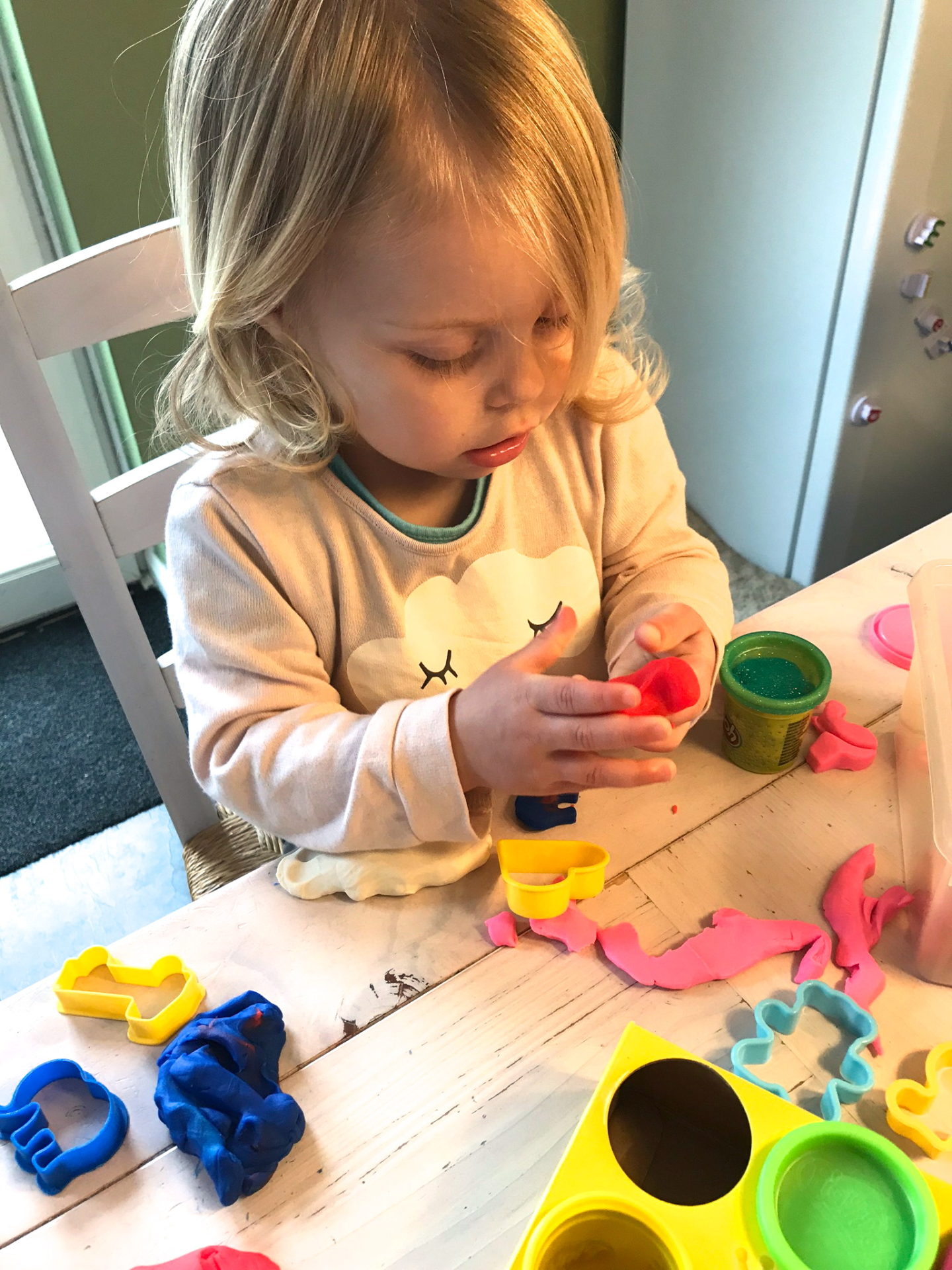 Two year old sitting at a table, playing with Play Doh