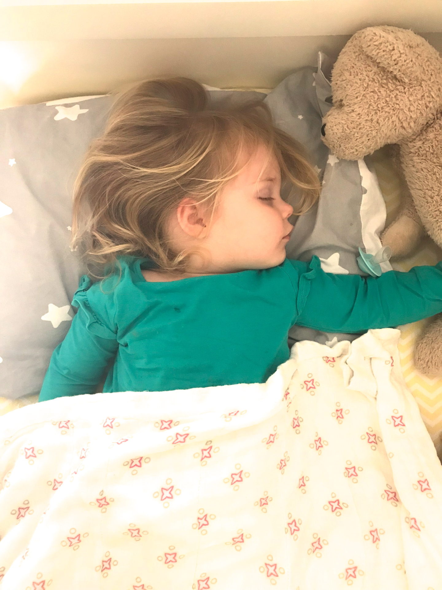 Two year old sleeping in bed with teddy