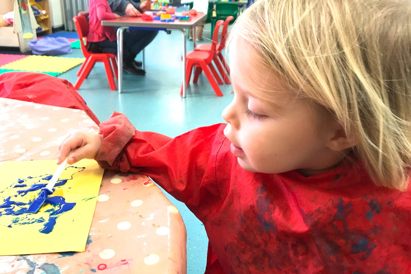 Two year old in an apron, painting