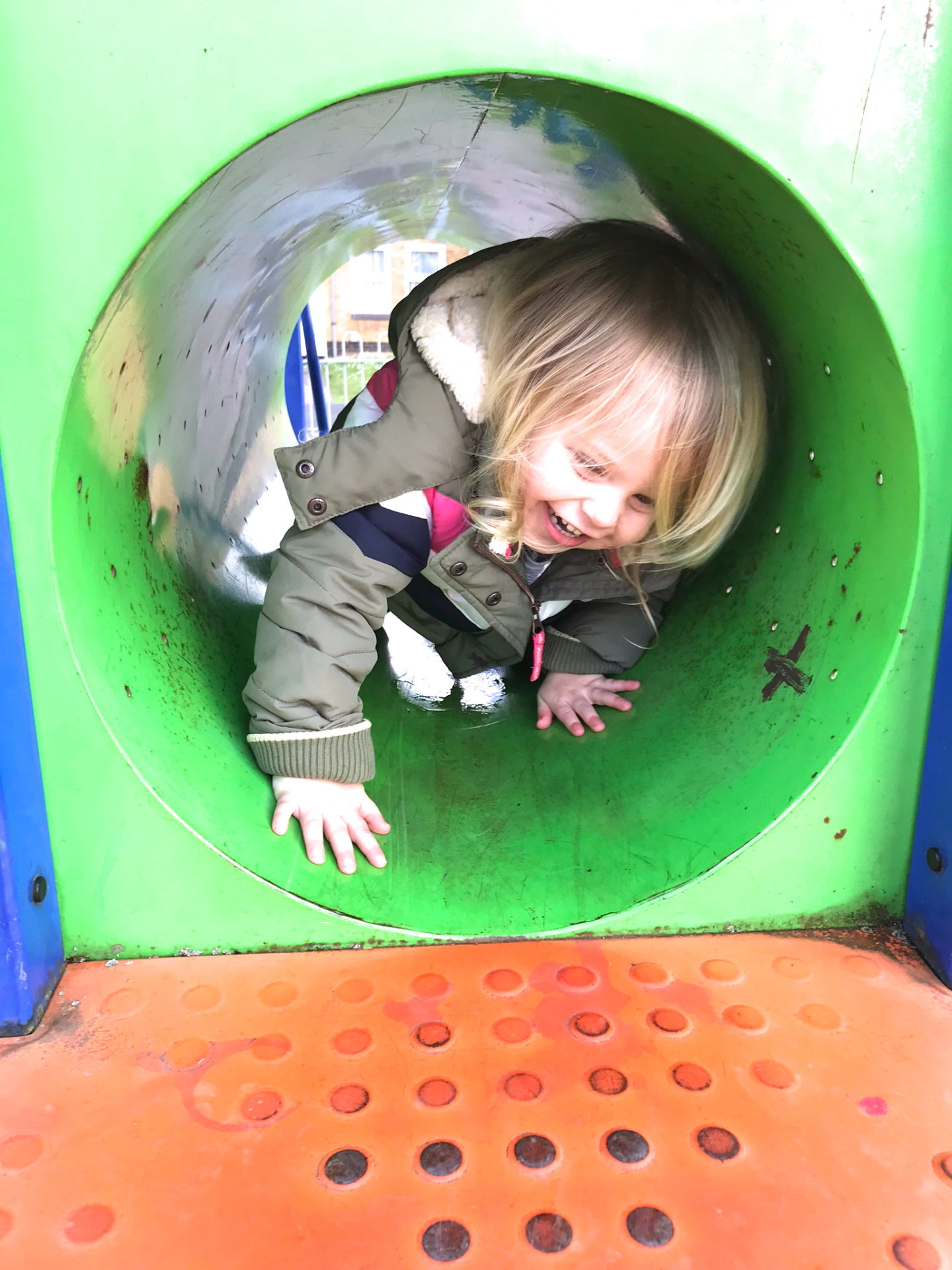 Two year old crawling through a tunnel in a playground