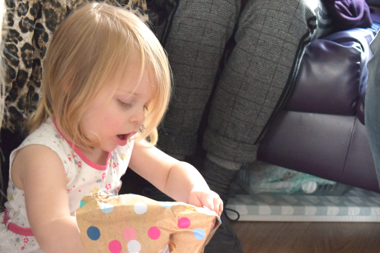Two year old in a party dress, opening a present