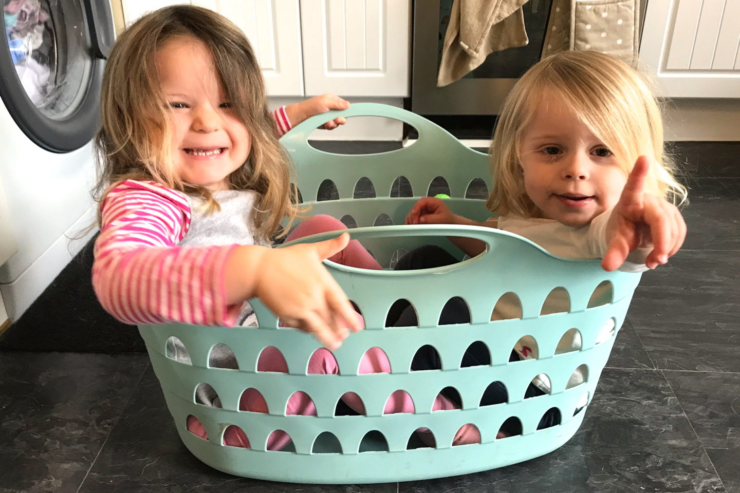 two sisters sitting in a washing basket, laughing