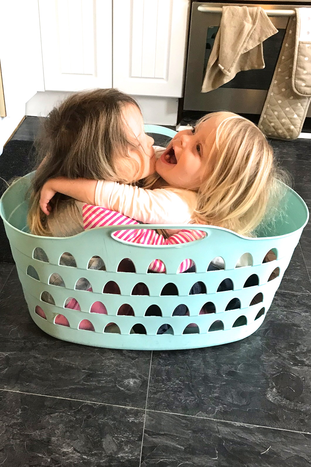 two sisters sitting in a washing basket, cuddling