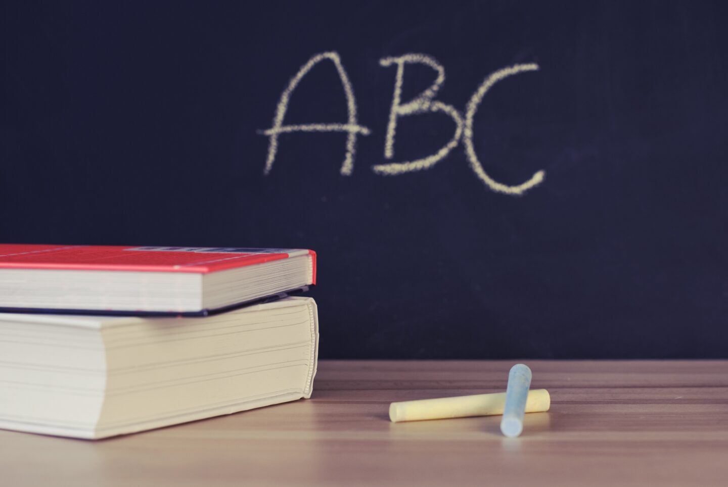Blackboard showing ABC written in chalk with books on a desk