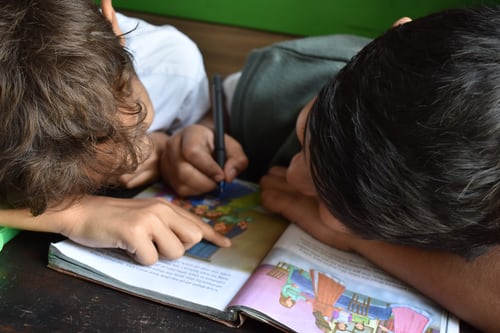 two boys looking at a school book together